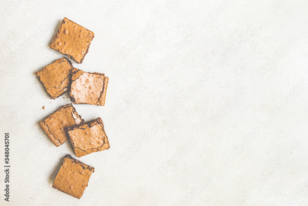 Top view of freshly baked home made brownie cake cut in squares over white rustic background. Copy space.