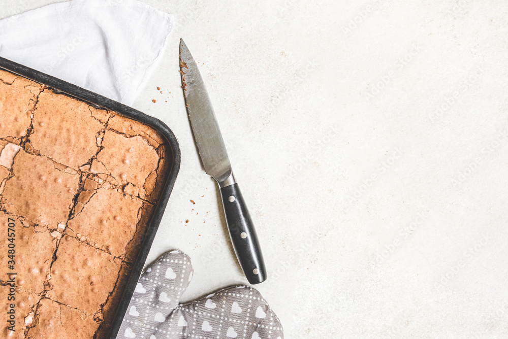 Top view of freshly baked home made brownie cake cut in squares over white rustic background. Copy space.