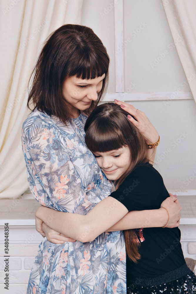 Warming and relaxing near fireplace. Mother and daughter hugging. Concept of family , motherhood, interior, home, childhood, mother's day, children's day Warming and relaxing near fireplace. Mother and daughter hugging. Concept of family , motherhood, interior, home, childhood, mother's day, children's day