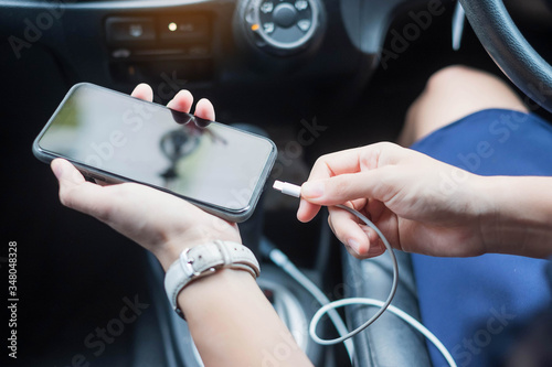 Woman charging smartphone in car. Technology and transportation concepts