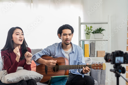 Couple vlog influencer performancing music and girl singing show to streaming internet online audience listening at home. Man playing guitar and woman sing a song. Home entertainer and blogger concept