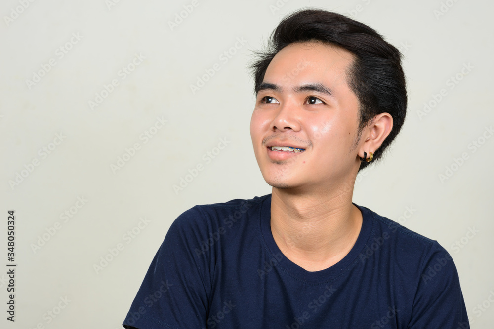 Portrait of happy young Asian man with braces thinking Portrait of happy young Asian man with braces thinking