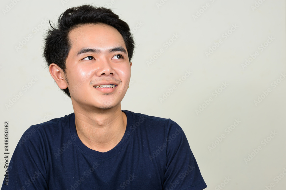Portrait of happy young Asian man with braces thinking Portrait of happy young Asian man with braces thinking