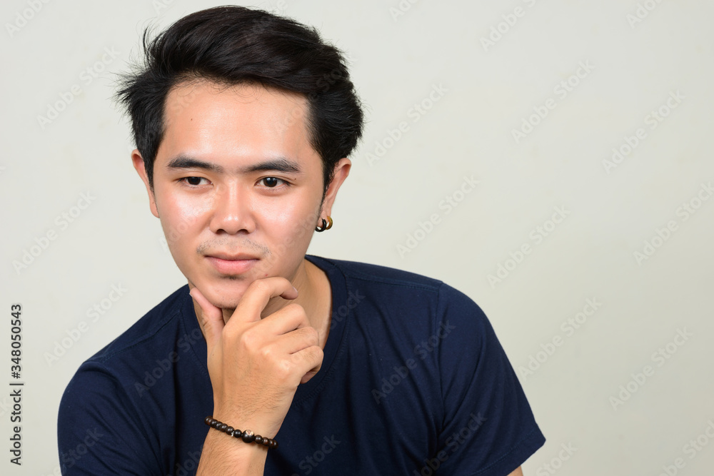 Portrait of young Asian man thinking and looking up Portrait of young Asian man thinking and looking up