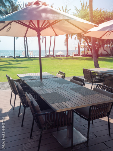 Wooden dining table and chairs with beach umbrella with sea view.