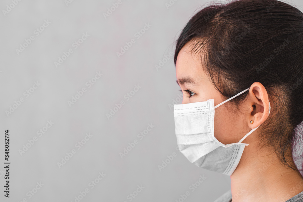 Little asian girl wearing sterile medical mask for protect Covid-19 isolated on gray background. Copy space. Little asian girl wearing sterile medical mask for protect Covid-19 isolated on gray background. Copy space.