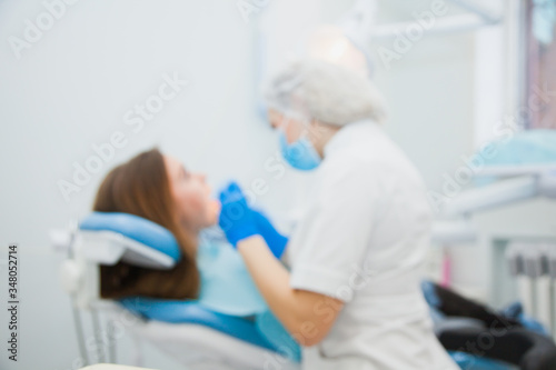 Young female dentist curing patient's teeth filling cavity