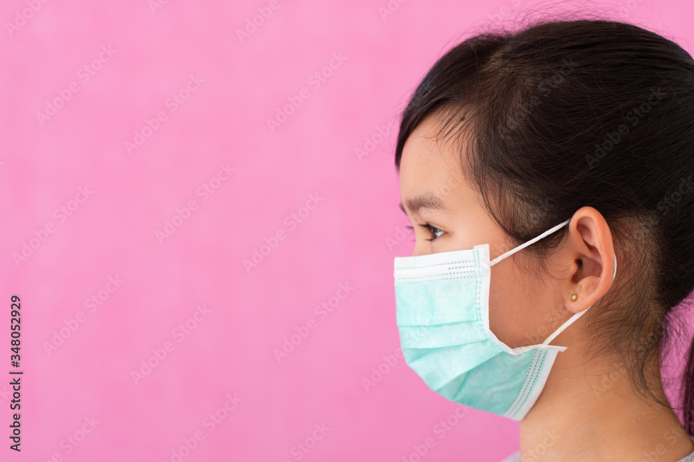 Little asian girl wearing sterile medical mask for protect Covid-19 isolated on pink background. Copy space. Little asian girl wearing sterile medical mask for protect Covid-19 isolated on pink background. Copy space.