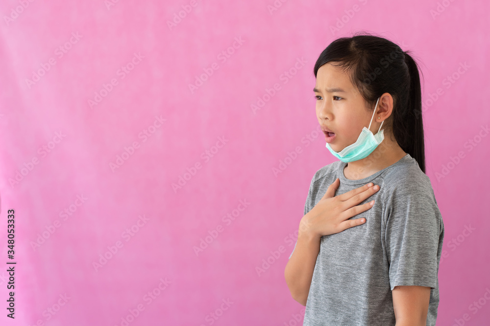 Asia little girl wearing hygienic mask to prevent the virus, PM2.5, Coronavirus, (2019-nCoV). Asian little girl feeling unwell and coughing isolated on pink background. Asia little girl wearing hygienic mask to prevent the virus, PM2.5, Coronavirus, (2019-nCoV). Asian little girl feeling unwell and coughing isolated on pink background.