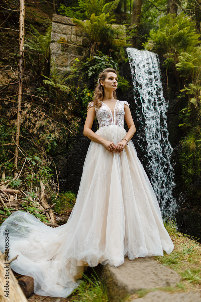 portrait of a young bride on the background of a waterfall