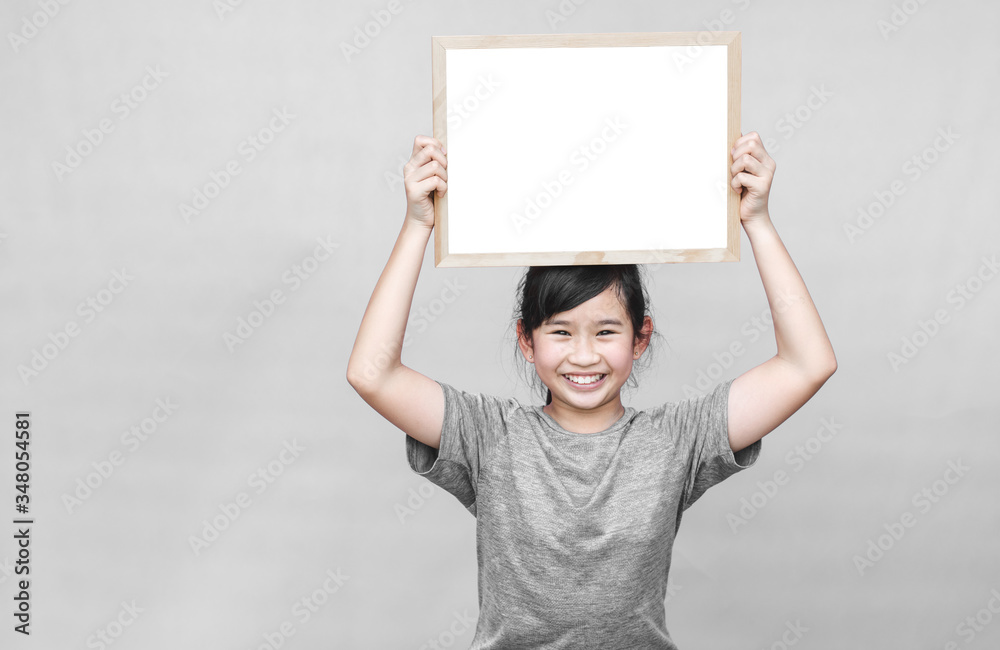 Little asian girl holding whiteboard isolated on gray background. Little asian girl holding whiteboard isolated on gray background.