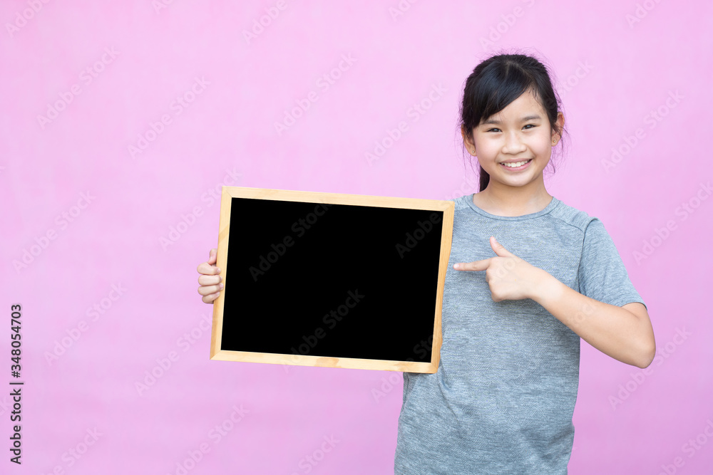 Little asian girl holding blackboard isolated on pink background. Little asian girl holding blackboard isolated on pink background.
