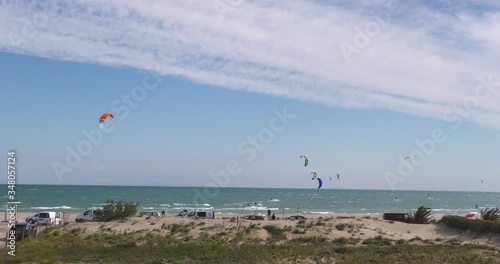 Several people practicing kitesurfing with candles of different colors