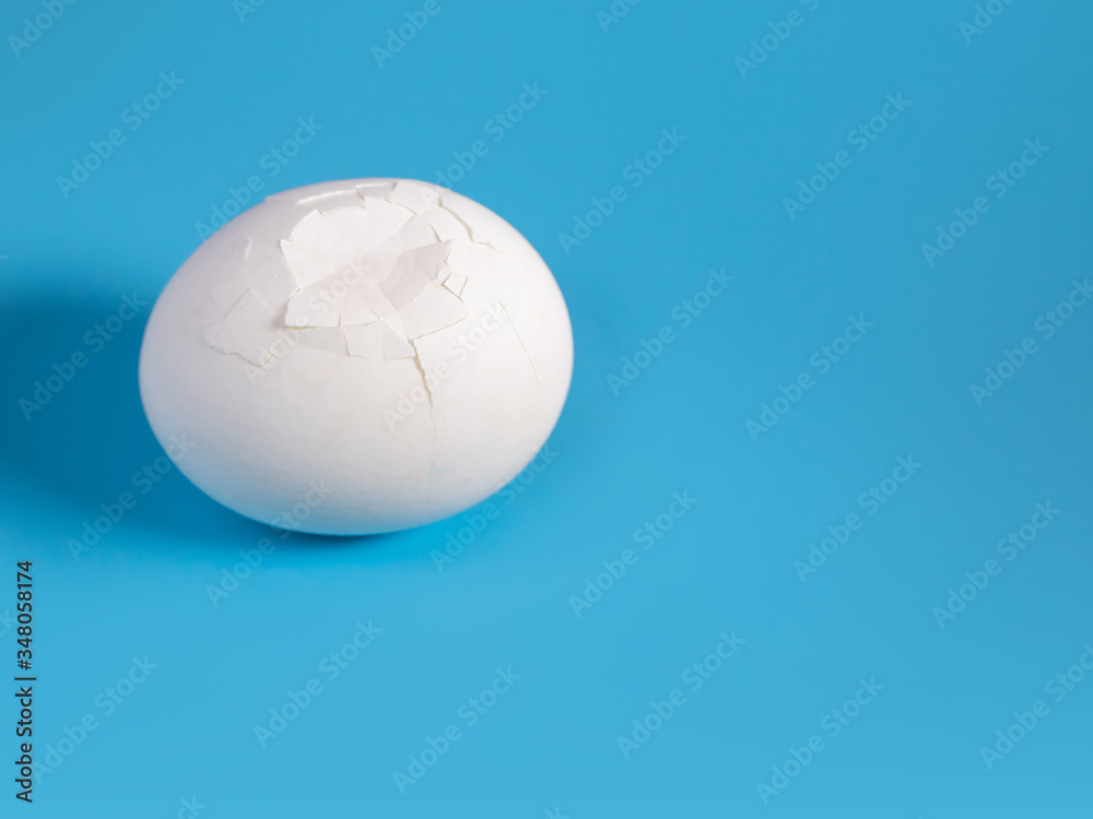 a cracked white large egg on a blue background on the left of the frame a cracked white large egg on a blue background on the left of the frame