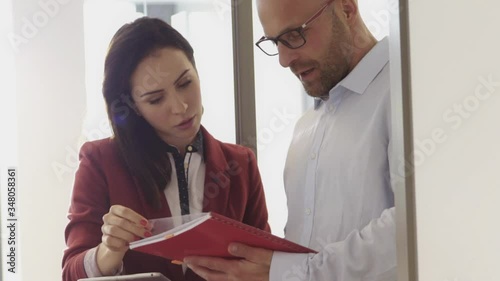 Businessman and businesswoman talking over red file in office meeting