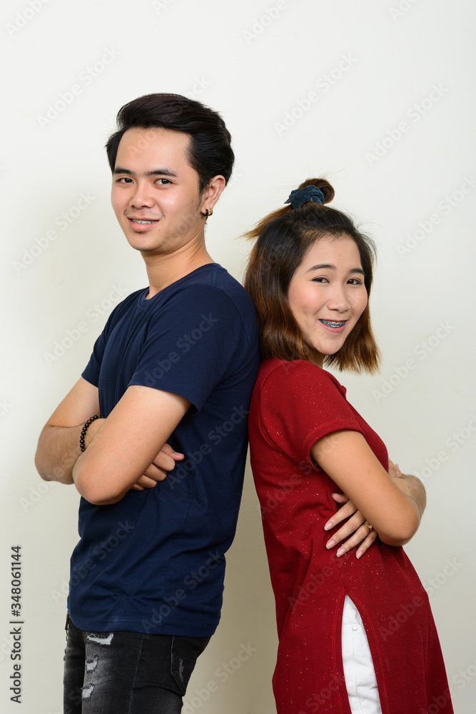Portrait of happy young Asian couple leaning on each other with arms crossed Portrait of happy young Asian couple leaning on each other with arms crossed