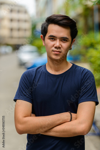 Portrait of young Asian man with arms crossed outdoors