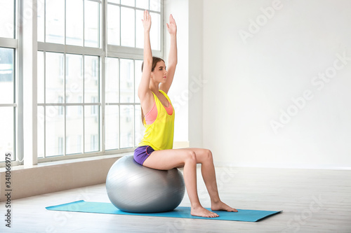 Sporty young woman training with fitball at home photo