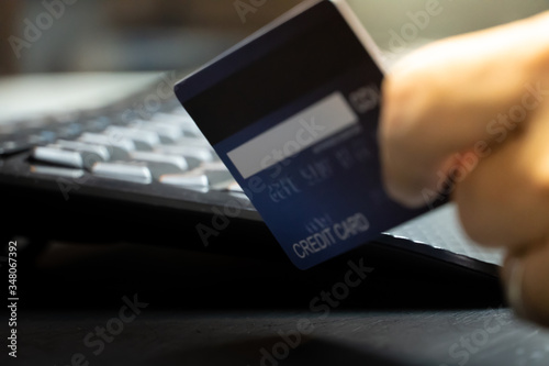 close up Shallow focus hand hold Credit Card on Computer keyboard. Background for E-commerce and online shopping concept.