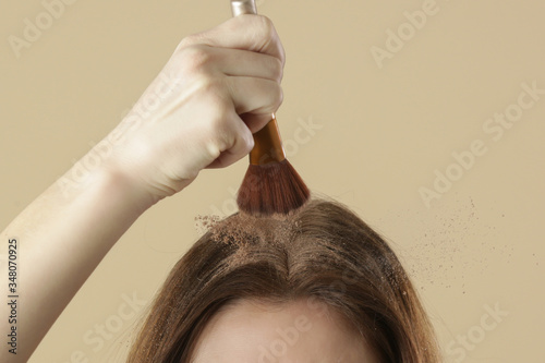 Photos Close up view at woman applaying natural dry shampoo on hair roots