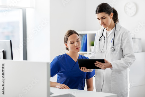 medicine  healthcare and technology concept - doctor with tablet pc computer talking to nurse at hospital