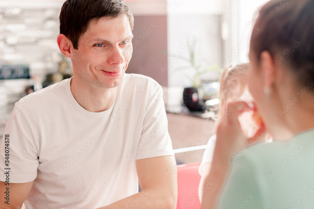 Fototapeta premium Happy family having breakfast in the kitchen at the table in sunny weather. The husband looks at his wife in love