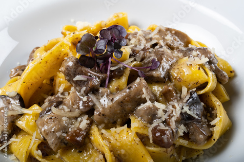 Fresh pappardelle pasta with porcini mushrooms and truffle scent. Parmesan and mozzarella cheese photo