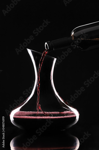 Pouring of tasty wine from bottle into glass on dark background