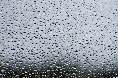 Rain drops on glass window. Dark grey textured background. Full frame macro photo. 
