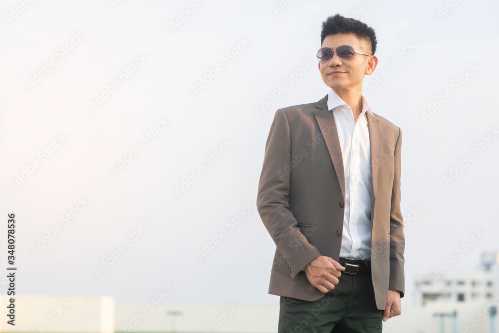 Asian successful confident business man standing on the top of the building in the city with happy and cheerful feeling for bright future Business and finance industry concept Asian successful confident business man standing on the top of the building in the city with happy and cheerful feeling for bright future Business and finance industry concept
