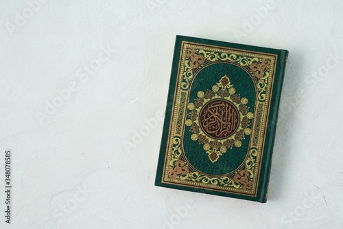 Holy Quran with written arabic calligraphy meaning of Al Quran on white background.