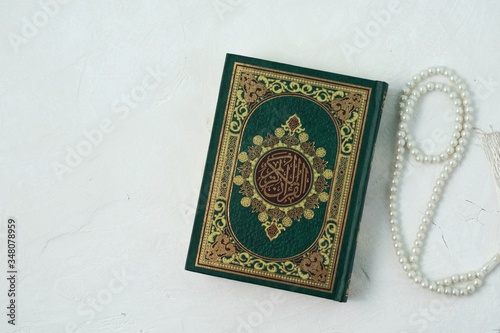 Holy Quran with written arabic calligraphy meaning of Al Quran on white background.