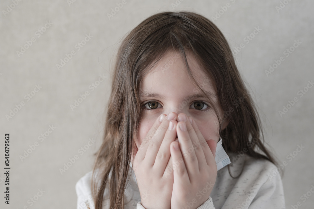 danger of coronavirus epidemic covid-19 spread little girl in mask wants to cough covering her mouth with hands danger of coronavirus epidemic covid-19 spread little girl in mask wants to cough covering her mouth with hands