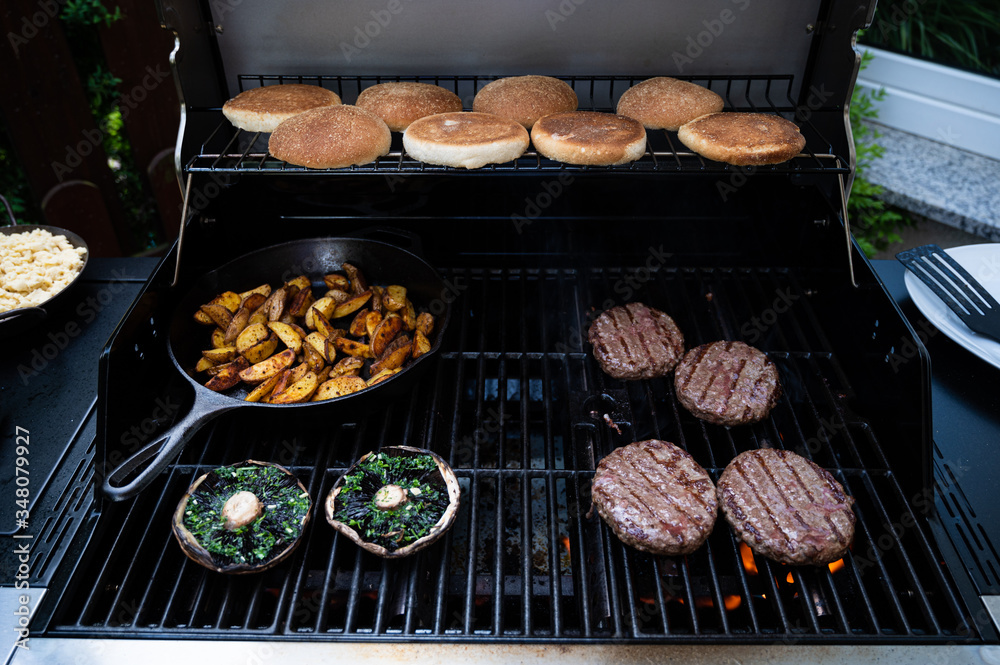 burgers on the bbq grill with potato wedges in pan and giant mushrooms burgers on the bbq grill with potato wedges in pan and giant mushrooms