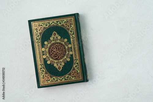 Holy Quran with written arabic calligraphy meaning of Al Quran on white background.