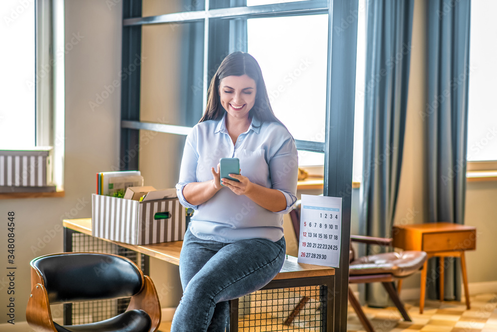 Young woman holding a smartphone and typing a message Young woman holding a smartphone and typing a message