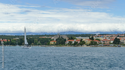 Panoramic view of coast with small village and yacht on sea after thunderstorm, Croatia
