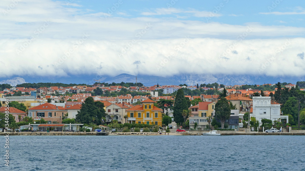 Croatian coast with small harbour town and mountains covered with low clouds, Zadar