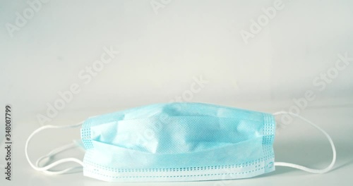 Tilt up of disposable earloop clinical blue face masks on white table photo