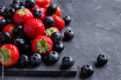 Strawberries and blueberries on a dark background close up