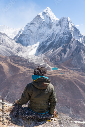 A trekker sitting and enjoying Ama Dablam mountain peak view from Nangkart Shank view point in Everest base camp trekking, Nepal
