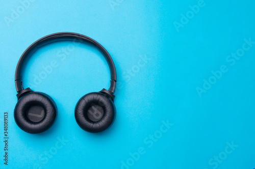 Black headphones on the left side of the photo. From above . Blue background. Copy space