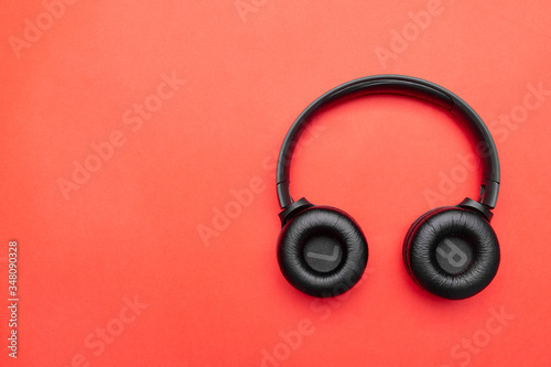 Black headphones on the right side of the photo. From above . Red background. Copy space