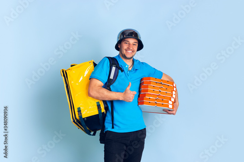 Thumb up, smiling. Emotions of caucasian deliveryman isolated on blue background. Contacless delivery service during quarantine. Man delivers food during isolation. Safety. Hurrying up. Looks fun. photo