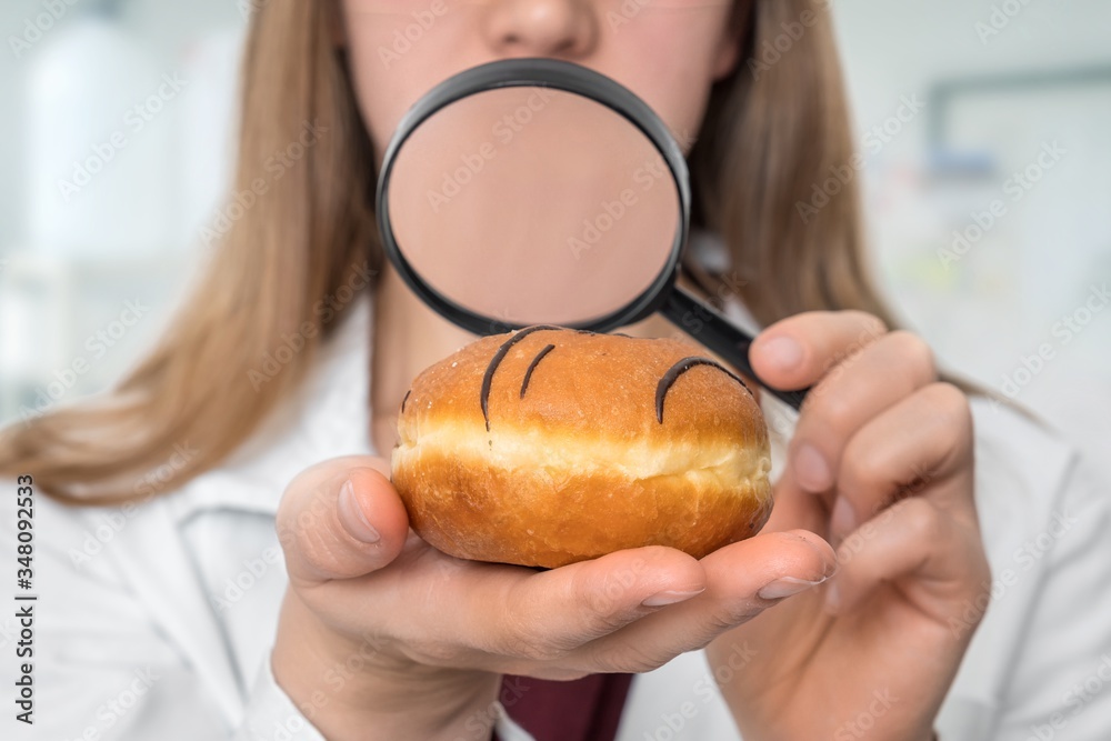 Scientist examines a doughnut with magnifying glass Scientist examines a doughnut with magnifying glass