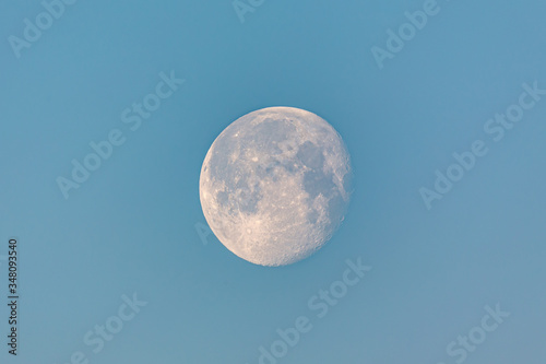 Almost full moon at early morning on a blue sky.