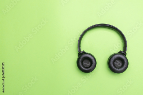 Black headphones on the right side of the photo. From above . Green background. Copy space