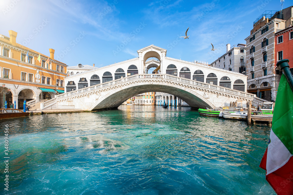 Blick auf die Rialto Brücke in Venedig, Italien, ohne Menschen, mit klarem, smaragdgrünen Wasser im Kanal und Sonnenschein
