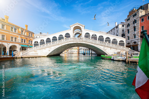 Blick auf die Rialto Brücke in Venedig, Italien, ohne Menschen, mit klarem, smaragdgrünen Wasser im Kanal und Sonnenschein