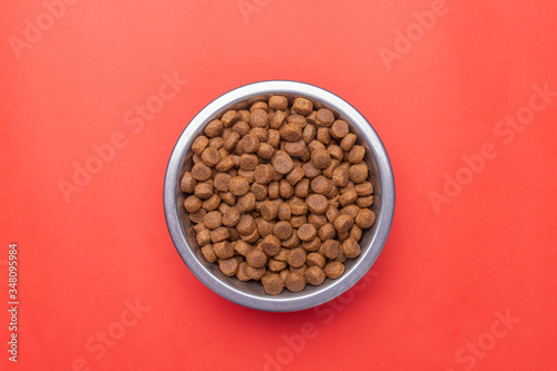 Dog food in a silver bowl. In the center. Red background. Copy, text sapce.